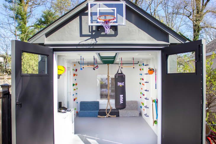 Garage that's been turned into big playroom with all kinds of sports equipment, climbing walls, sofa