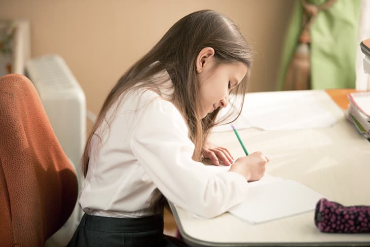 young girl writing letter at a desk