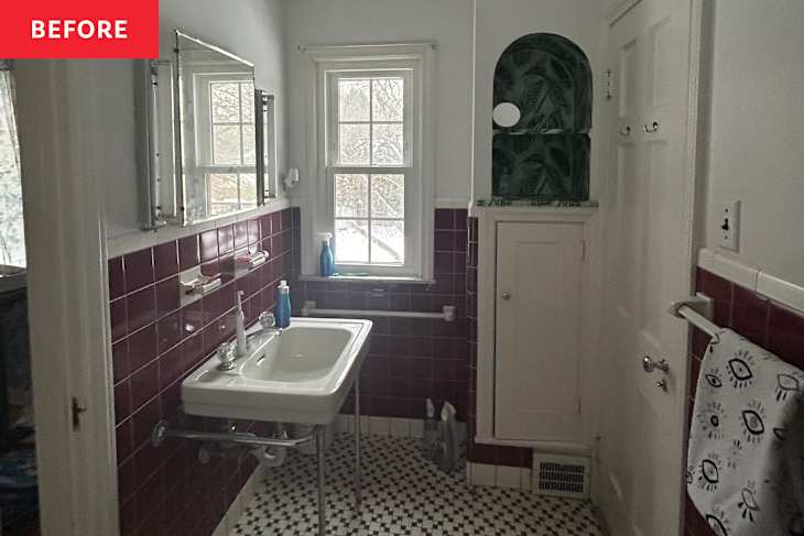 Bathroom with burgundy tiled walls, a white sink on a metal stand, and a window. A towel hangs on the door.