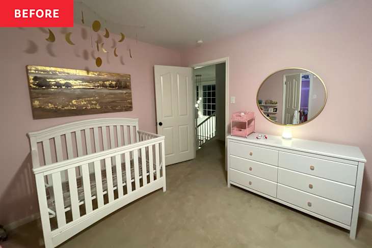 Nursery with a white crib, dresser, round mirror, pink walls, and gold moon decorations hanging from the ceiling.