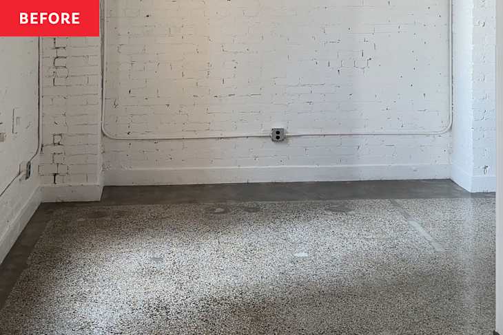Empty room with white brick walls, exposed electrical outlets, and a textured concrete floor.