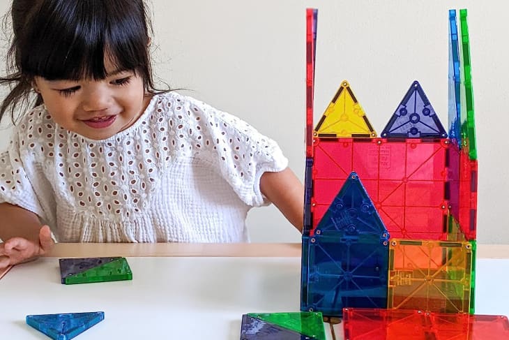 Little girl playing with set of magna tiles
