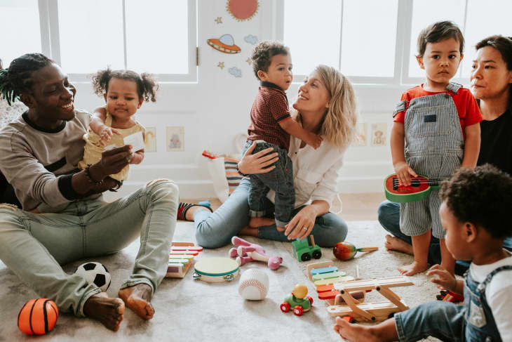 Children and adults playing with musical toys and balls in a bright playroom.