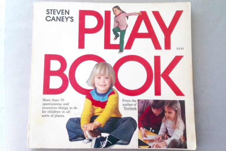 Children's activity book cover with a child in a colorful sweater, large red text, and kids drawing.