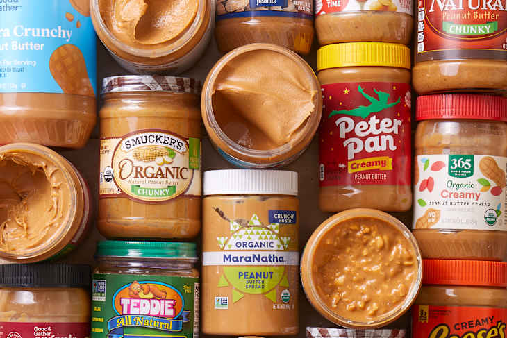overhead shot of peanut butter jars on top of each other with some jars opened showing the inside