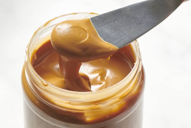 cookie butter being scooped out of a reused peanut butter jar