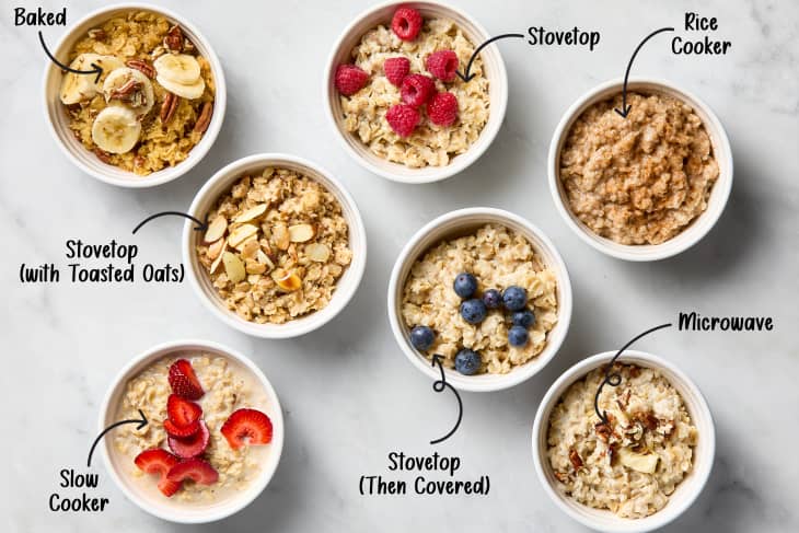 Seven bowls of oatmeal with various toppings: bananas, pecans, raspberries, almonds, blueberries, strawberries, and cinnamon.