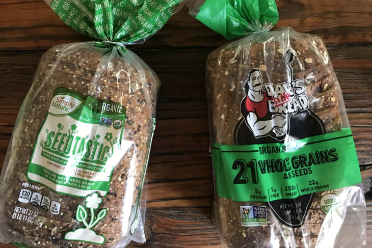 Two loaves of organic bread on a wooden table: Simply Nature Seedtastic and Dave's Killer Bread 21 Whole Grains.