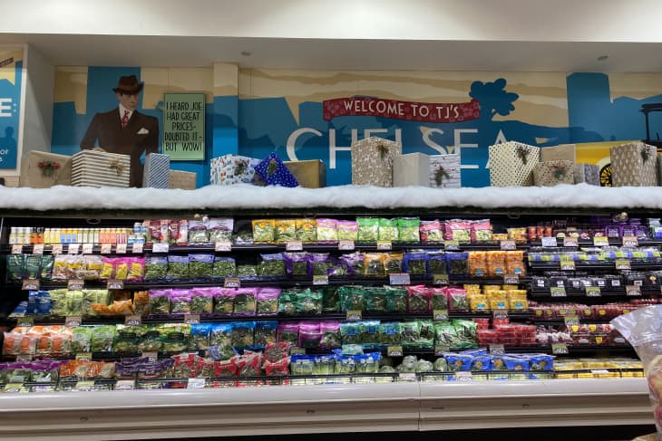 Grocery store produce section with colorful packaged vegetables and a decorative display above.