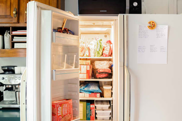 Refrigerator, with freezer door opened. Food in freezer has been neatly organized. On the fridge door the freezer inventory checklist is hanging.