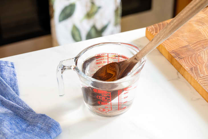 Wooden spoon sitting in a measuring cup with hot water