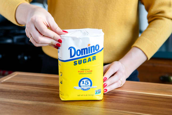 Someone holding a bag of sugar.