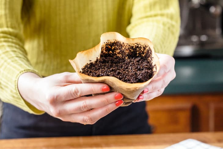 Someone holding a coffee filter with spent gounds.