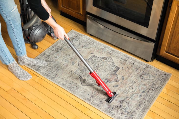 Someone vacuuming a kitchen rug.