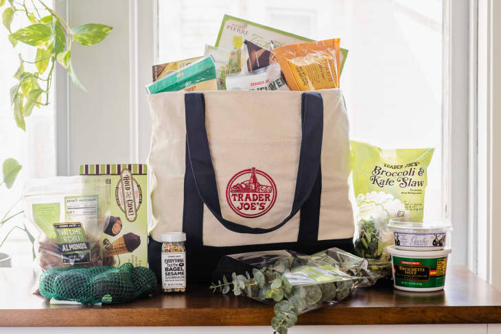 Trader Joe's canvas bag on counter top filled with grocery items as well as some items surrounding bag on counter top.