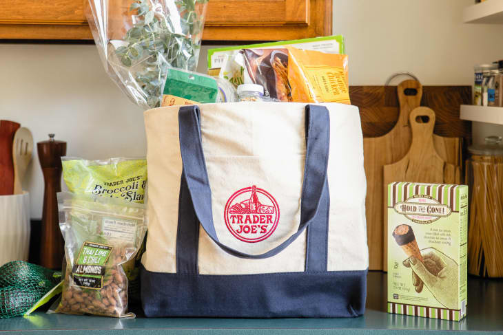 Trader Joe's canvas bag filled with groceries on countertop; some grocery items displayed on countertop.