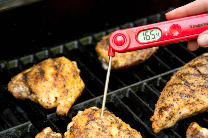 Checking temperature of grilled chicken with a thermometer