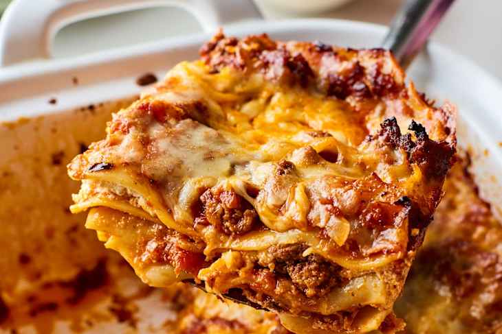 Slice of lasagna being lifted out of pan of lasagna