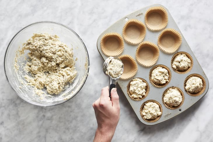 Muffin batter is divided between muffin pans.