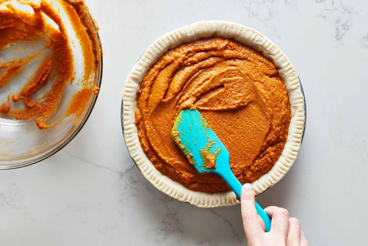 With a spatula, the pumpkin pie filling is spread with in the pie shell.