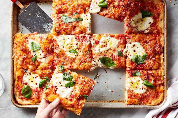 Hands taking slices of focaccia pizza.