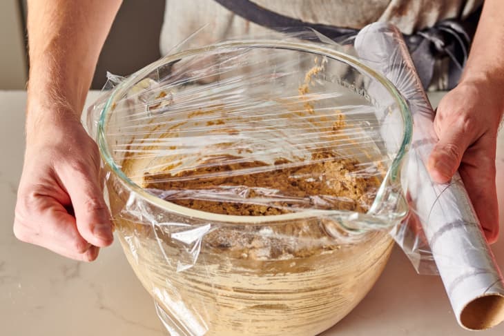someone is wrapping the bowl with plastic wrap