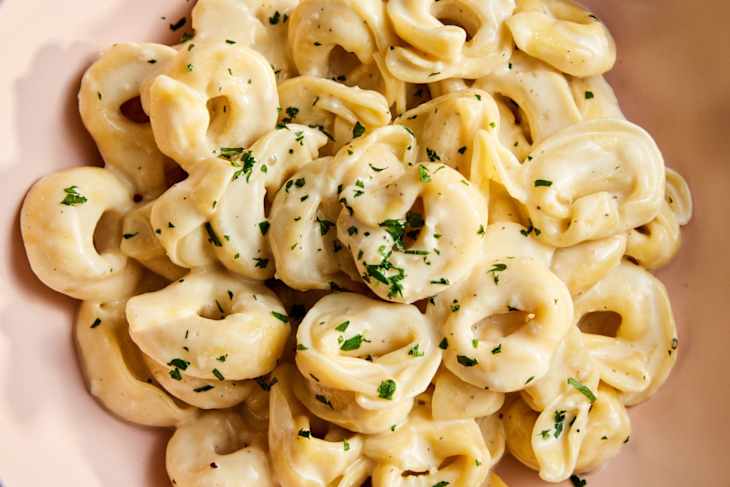 Tortellini Alfredo in pink bowl with herb garnish