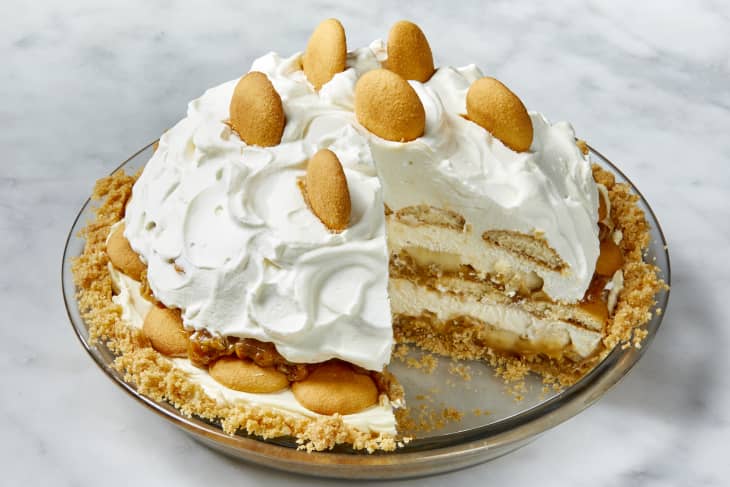 Angled view of banana pudding pie in a glass pie plate, with one slice taken out.