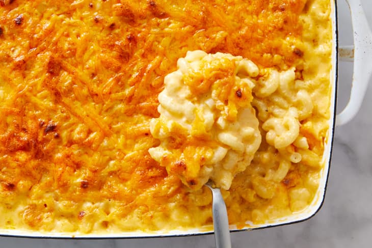 A big scoop of baked mac and cheese being taken out of the baking dish.