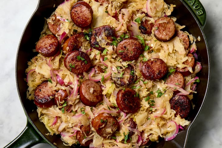 Overhead shot of cooked sauerkraut and sausage in a cast iron pan.