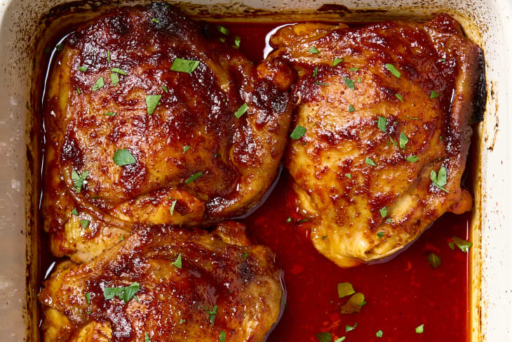 overhead shot of three harissa orange chicken thighs in a small white baking dish.