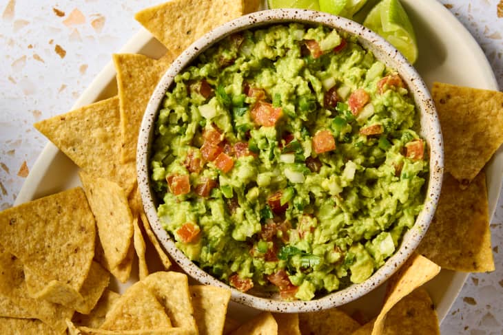 overhead shot of guacamole in a small bow surrounded by tortilla chips.