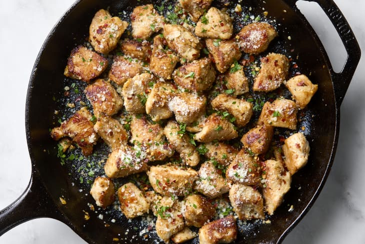 An overhead shot of chicken garlic parmesan bites in a cast iron skillet on a marble surface