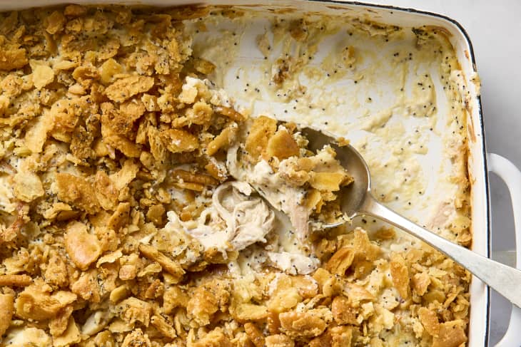 An overhead view of a white casserole dish of poppyseed chicken with a spoonful coming out.