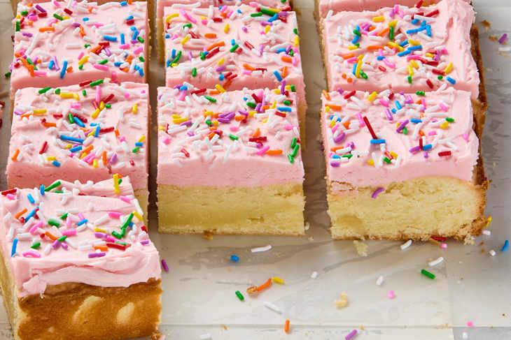 A low angle view of sour cream bar cookies with pink frosting and rainbow sprinkles