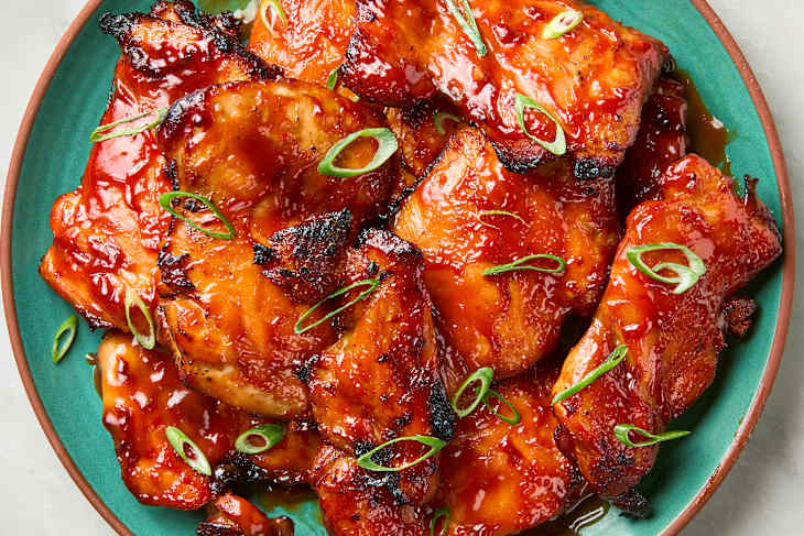 overhead shot of filipino barbecue chicken on s teal plate, topped with green onion