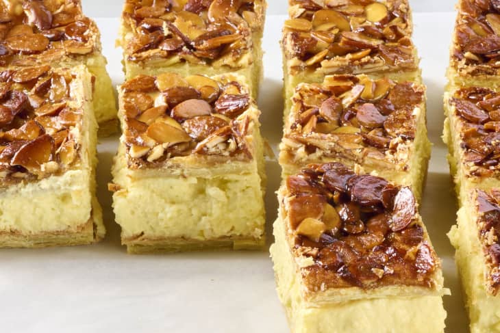 Angled photo of bee sting dessert bars showing the caramelized sliced almond topping, the pudding center, and the flaky puff pastry bottom and top layers.