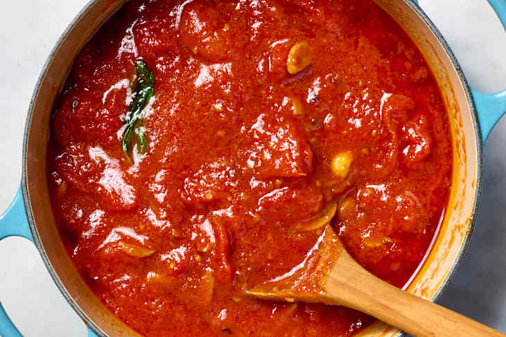 overhead shot marinara in a large pot with a wooden spoon in it