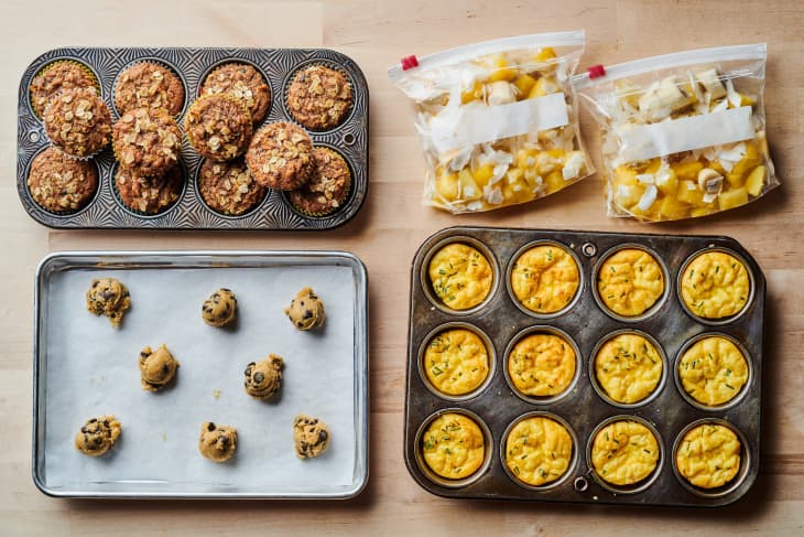 Power hour freezer snacks laid on countertop. Top left to right: morning glory muffins, 2 bags of Piña Colada Smoothie Packs. Bottom left: chocolate chip cookie dough, pan of 3-Cheese Frittata Cups.