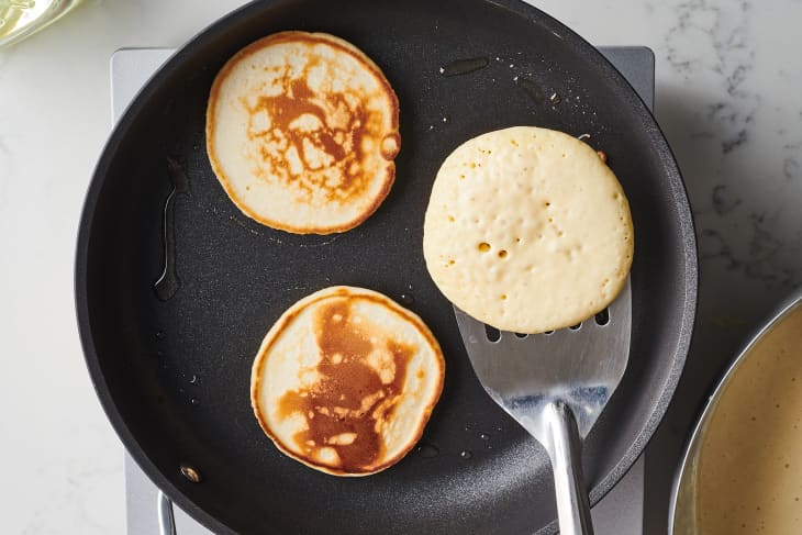 someone is flipping a pancake in a cast iron pot