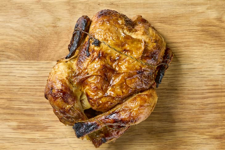 overhead shot of a rotisserie chicken on a wood cutting board.