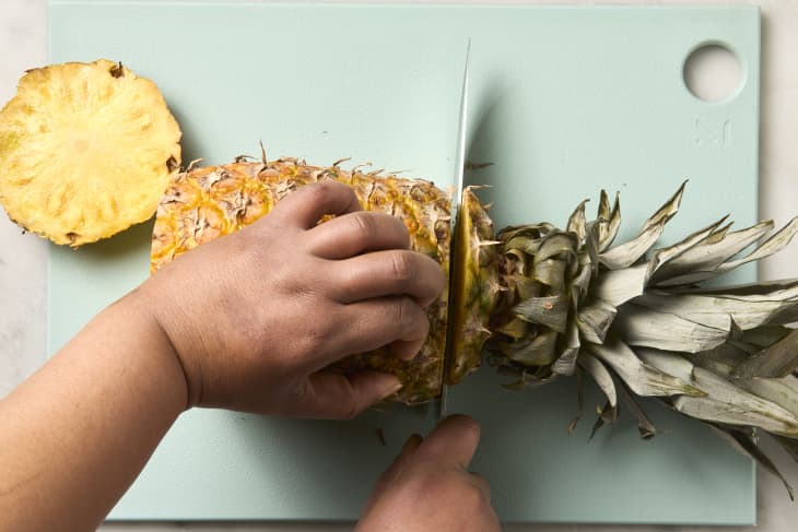 overhead shot of a full pineapple with the top being sliced off.