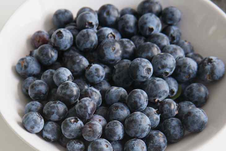 A close-up of fresh blueberries piled in a white bowl, showcasing their deep blue color and round shape.