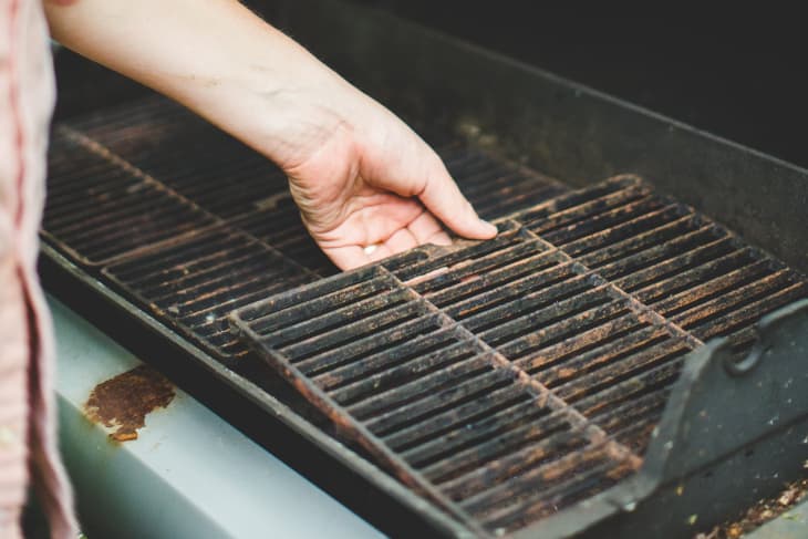 Hand lifting a grill grate from the grill