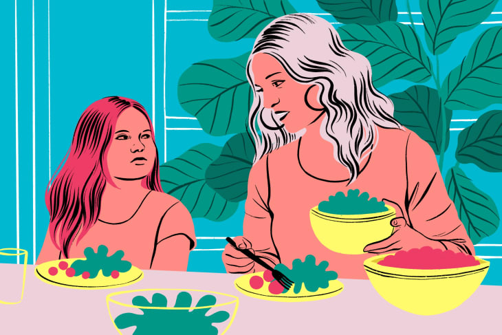 Mother and daughter at a table with salad bowls, vibrant leaves in the background.