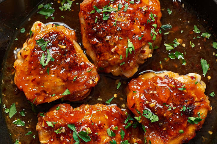 Chicken thighs glazed with apricot preserves and garnished with chopped fresh cilantro in a pan