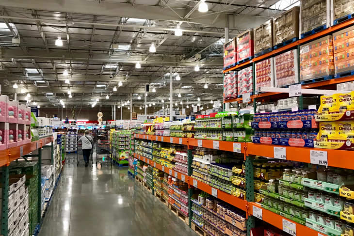 Grocery store aisle with shelves of vitamins, supplements, and bulk products under bright ceiling lights.