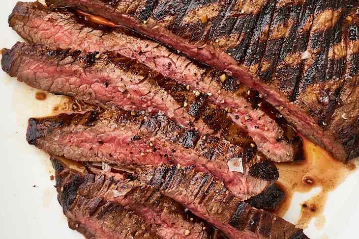 Steak with grill marks, partially sliced, on a platter