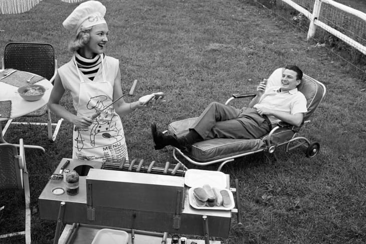 Vintage photo of woman grilling a hotdog with man in lounge chair nearby