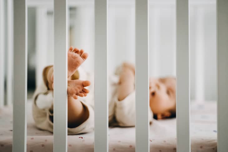 Baby sleeping in cot, little feet stepping on the fence of cot